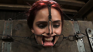 Busty red-haired chick gets locked in pillory and her pussy lips pinned with metal pegs