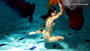 Fire redhead girl named Edwige swimming naked in a pool